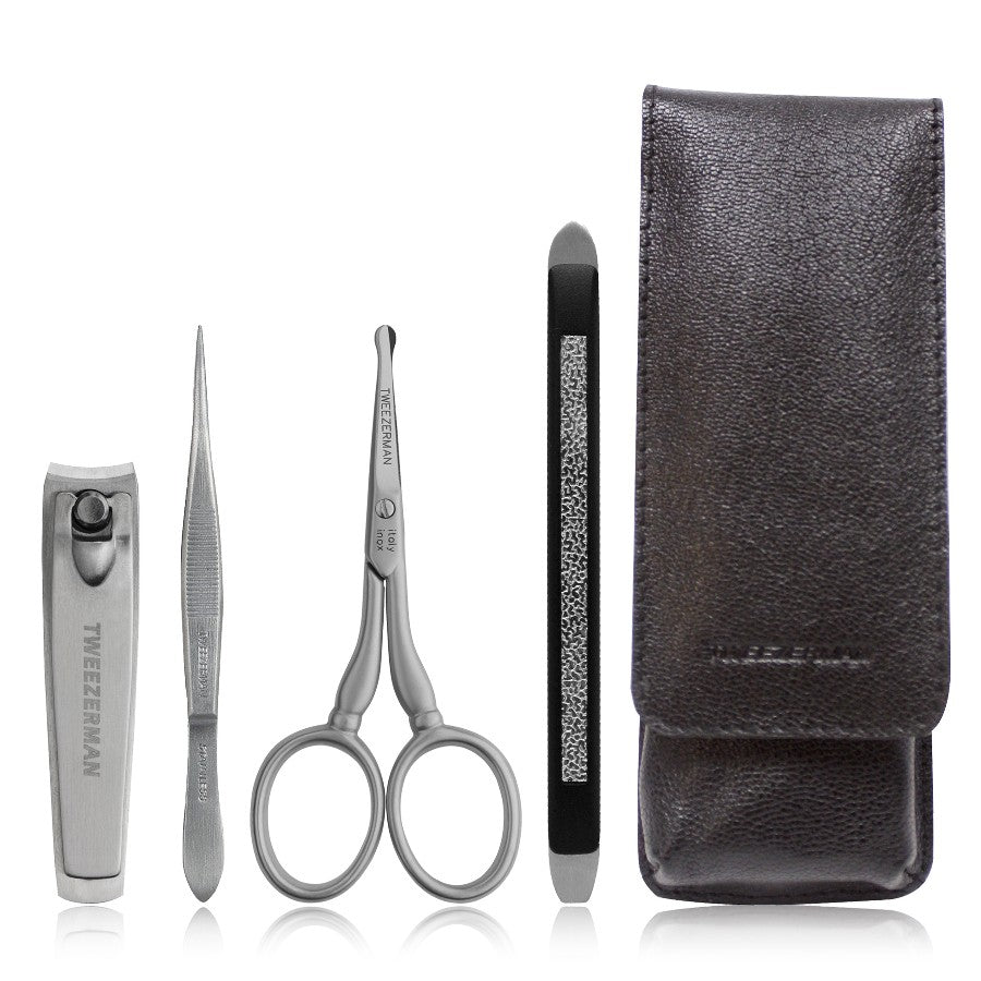 Yolaine Tweezerman Essential Grooming Kit with stainless steel nail scissors, tweezers, and grooming tools on a white background.