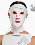 CurrentBody Skin LED Neck & Décolletage Mask emitting red light on the face and neck for skin rejuvenation.